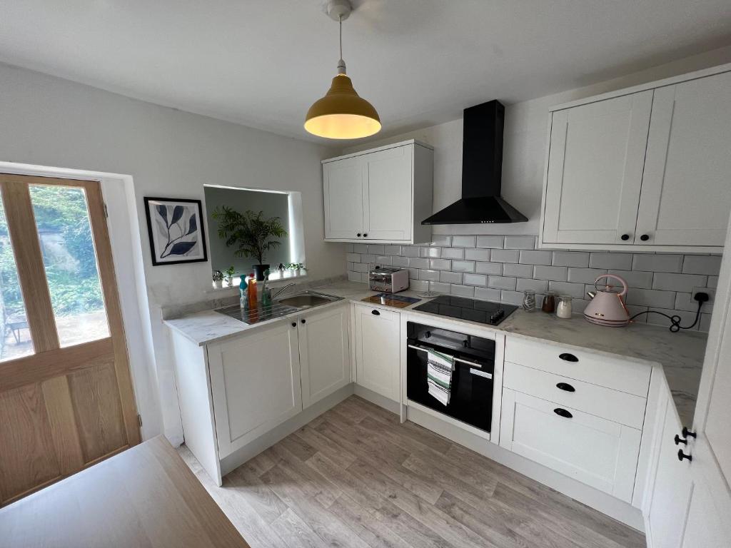 a kitchen with white cabinets and a stove top oven at Littlehampton House - 4 bedroom house sleeps 8 in Littlehampton