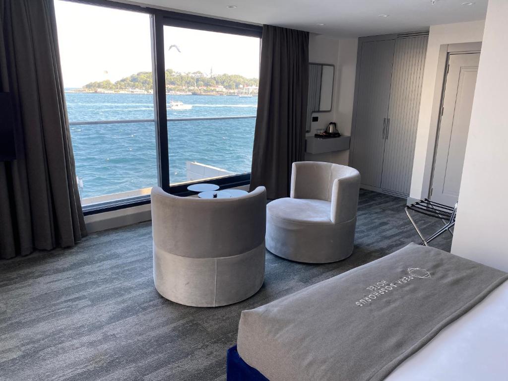 a hotel room with a bed and chairs and a large window at Pera Bosphorus Hotel in Istanbul