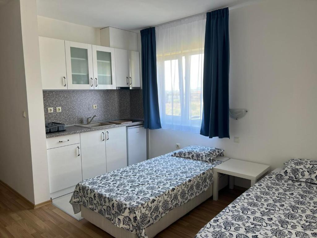 Cette chambre comprend deux lits et une cuisine avec des rideaux bleus. dans l'établissement Pretty House, à Sveti Vlas