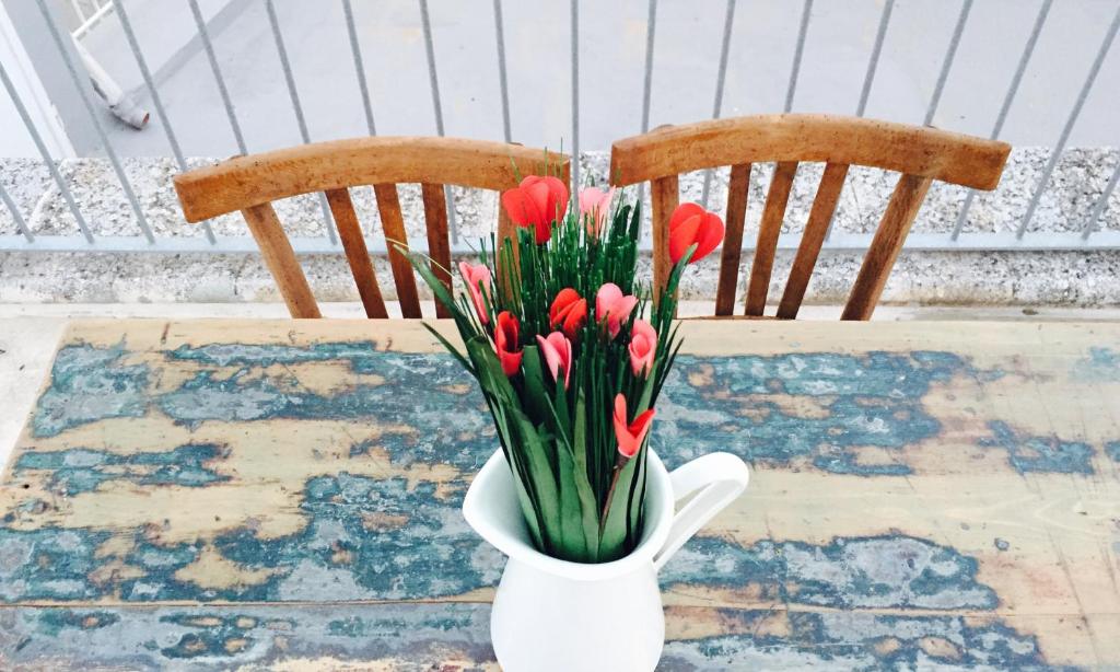 un jarrón de tulipanes rojos sobre una mesa con dos sillas en Borgo Albergo Capozzi 41 en Monopoli
