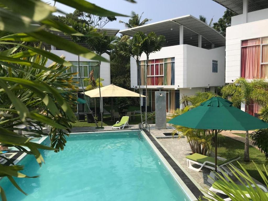 vista sulla piscina in un resort con ombrellone di Emerald Villas Weligama a Weligama