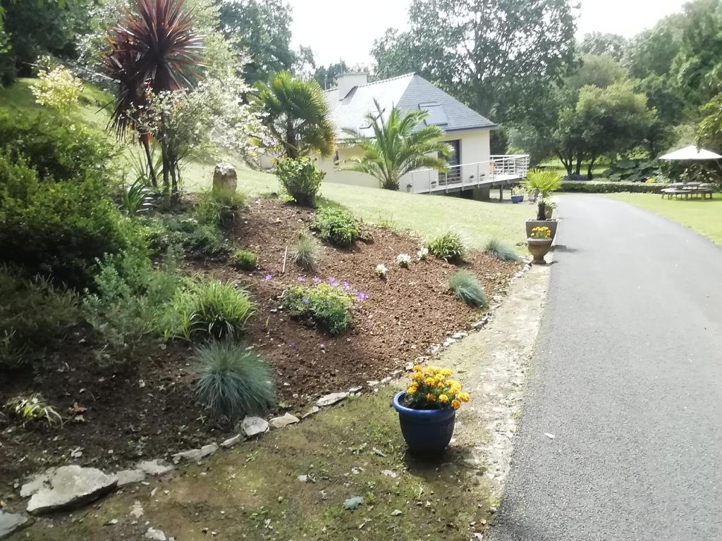 a garden with flowers in a pot on the side of a road at La maison au bord de l'eau in Plouigneau