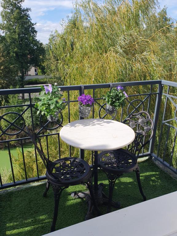 a white table and chairs on a balcony with flowers at Les toits de Bailly Disney Paris in Bailly-Romainvilliers