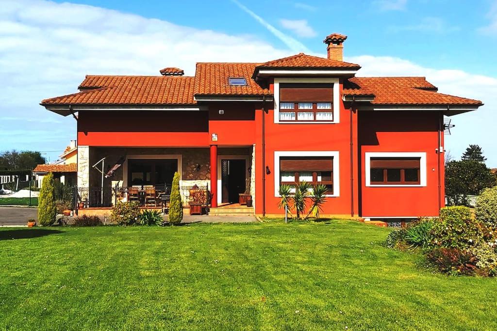 uma casa vermelha com um relvado verde em frente em Chalet Miranda. VV-1595-AS em Avilés