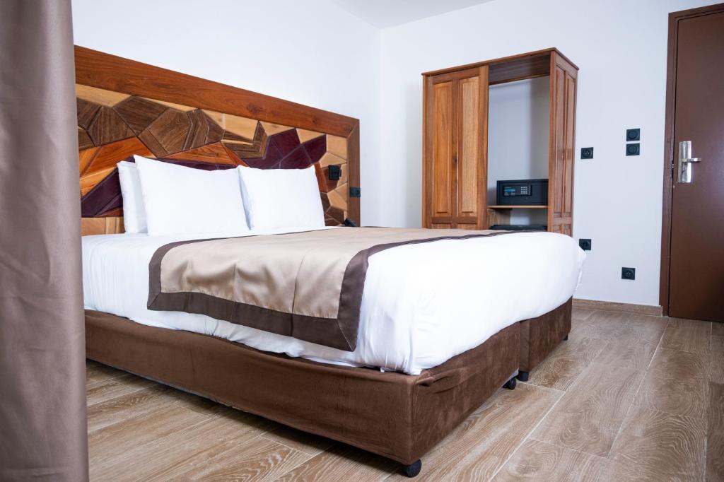a bedroom with a large bed with a wooden headboard at Hôtel Belle Terre Resort in Macouria
