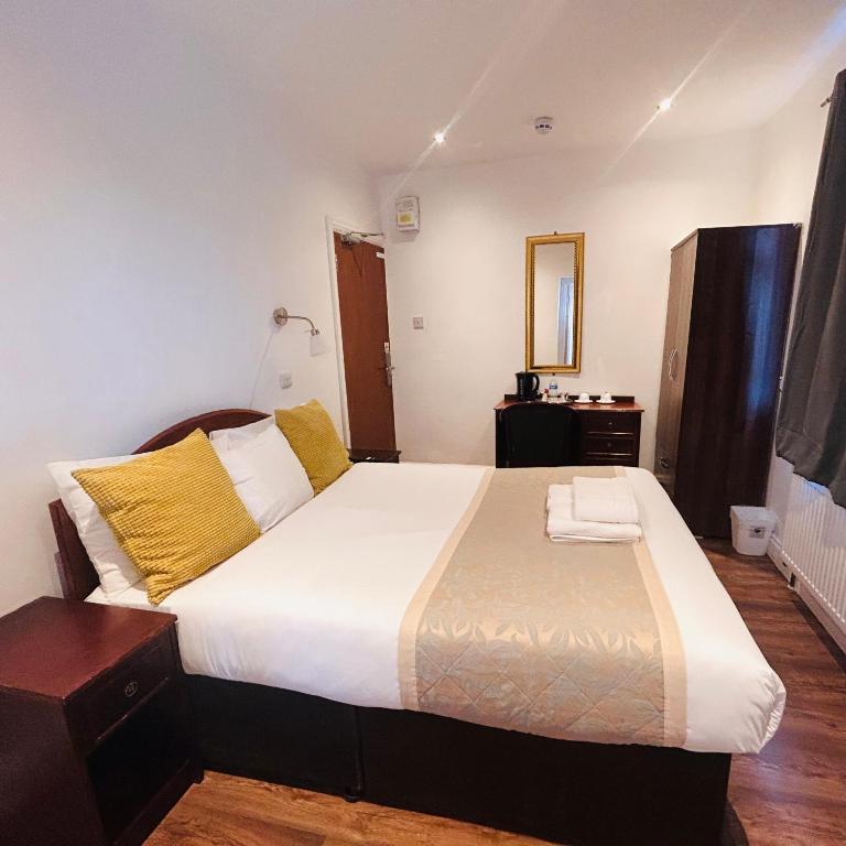een slaapkamer met een groot bed met gele kussens bij Sinai Hotel in Londen