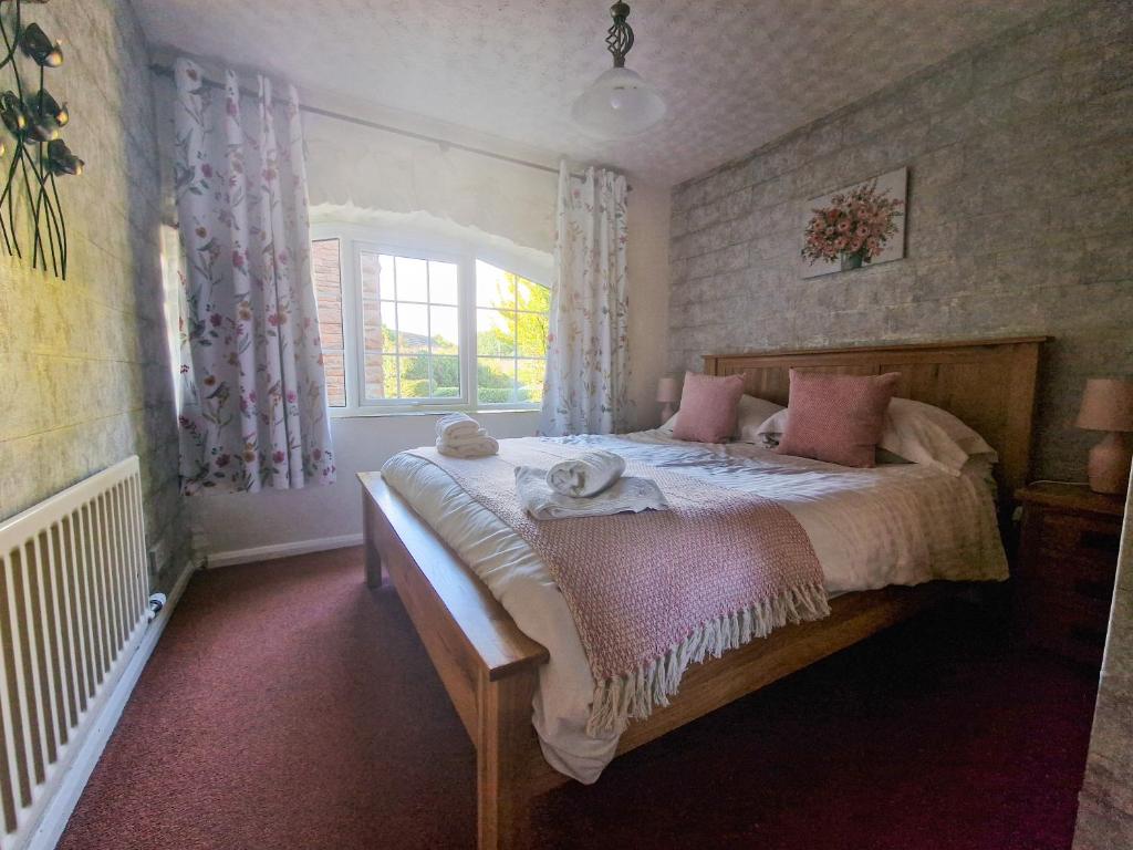 a bedroom with a bed with pink pillows and a window at Windale at Wetheral Cottages in Great Salkeld