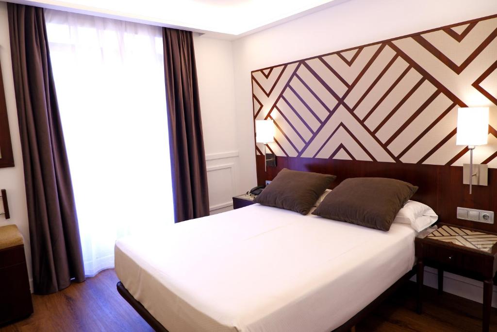 a bedroom with a large bed with a wooden headboard at Hotel Boutique Atrio in Valladolid