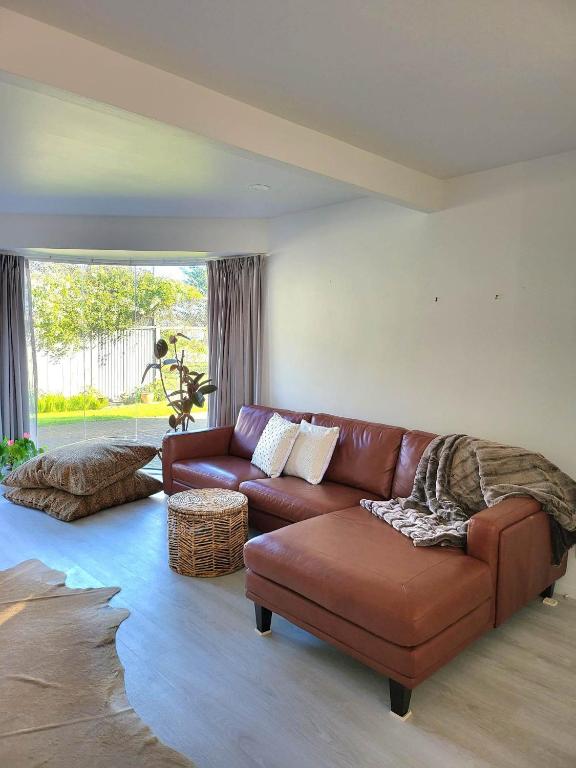 a living room with a brown leather couch at Oceanside Haven in Ohope Beach