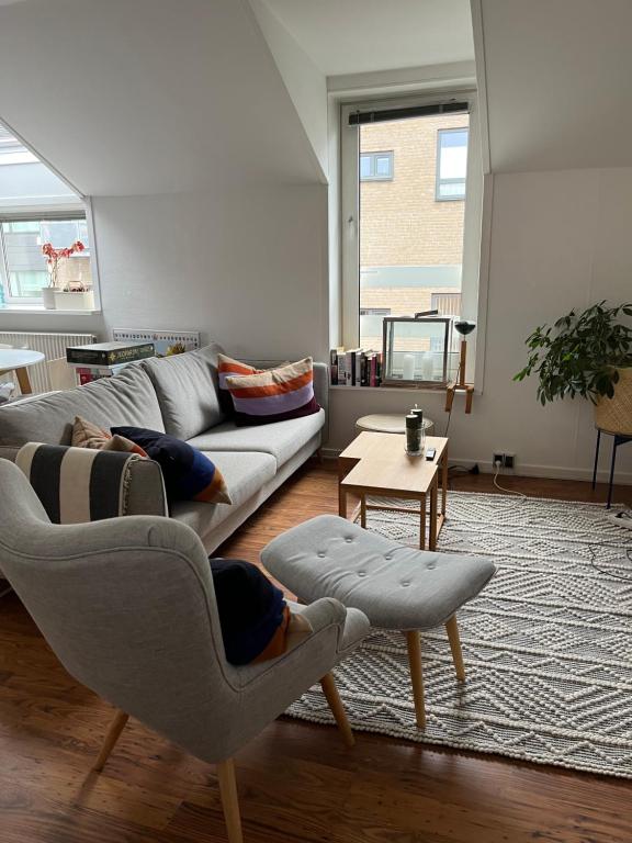uma sala de estar com um sofá e duas cadeiras em Skøn centralt beliggende lejlighed m.tagterrasse em Herning