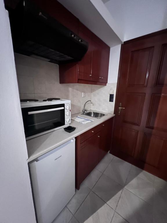 a kitchen with brown cabinets and a white microwave at Electra Studios in Palaiochora