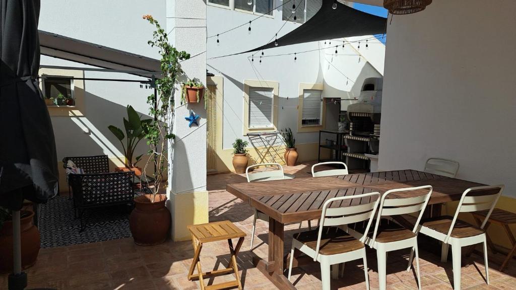 patio con mesa de madera y sillas en el balcón en Casa da Praia - Manta Rota, en Manta Rota