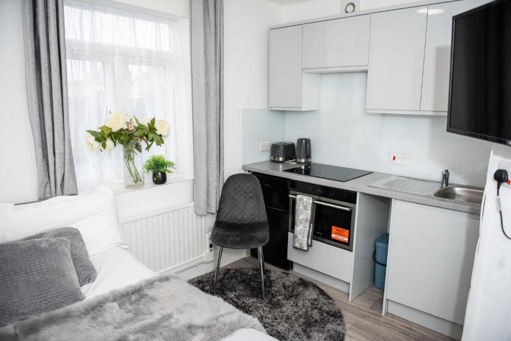 a kitchen with white cabinets and a chair in a room at Small But Cozy Studio, Great Tube Connection (D) in London