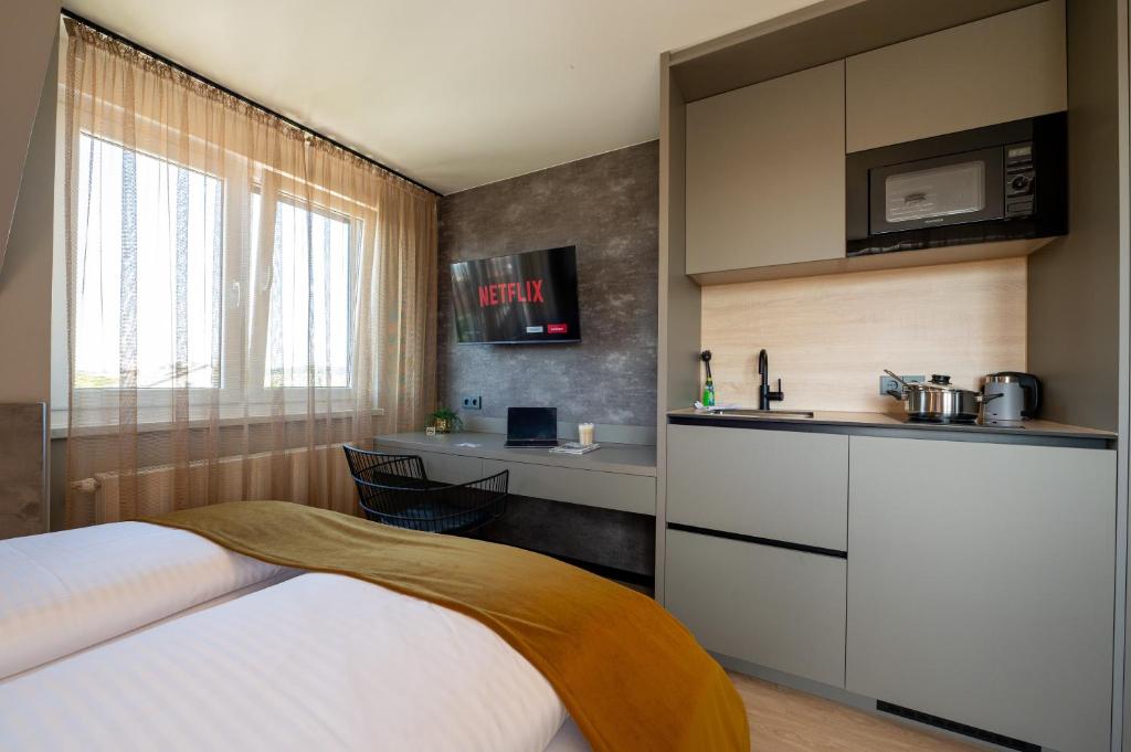 a bedroom with a bed and a kitchen with a counter at V Business Apartments Böblingen in Böblingen