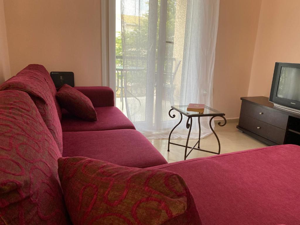 un soggiorno con divano rosso e TV di Vanilla Holiday House ad Alepoú