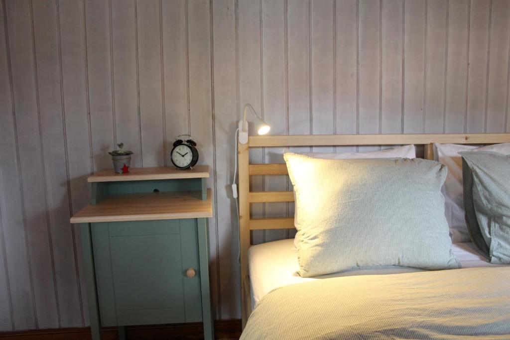 1 dormitorio con 1 cama y mesita de noche con reloj en Casinha do pinhal, en Colares