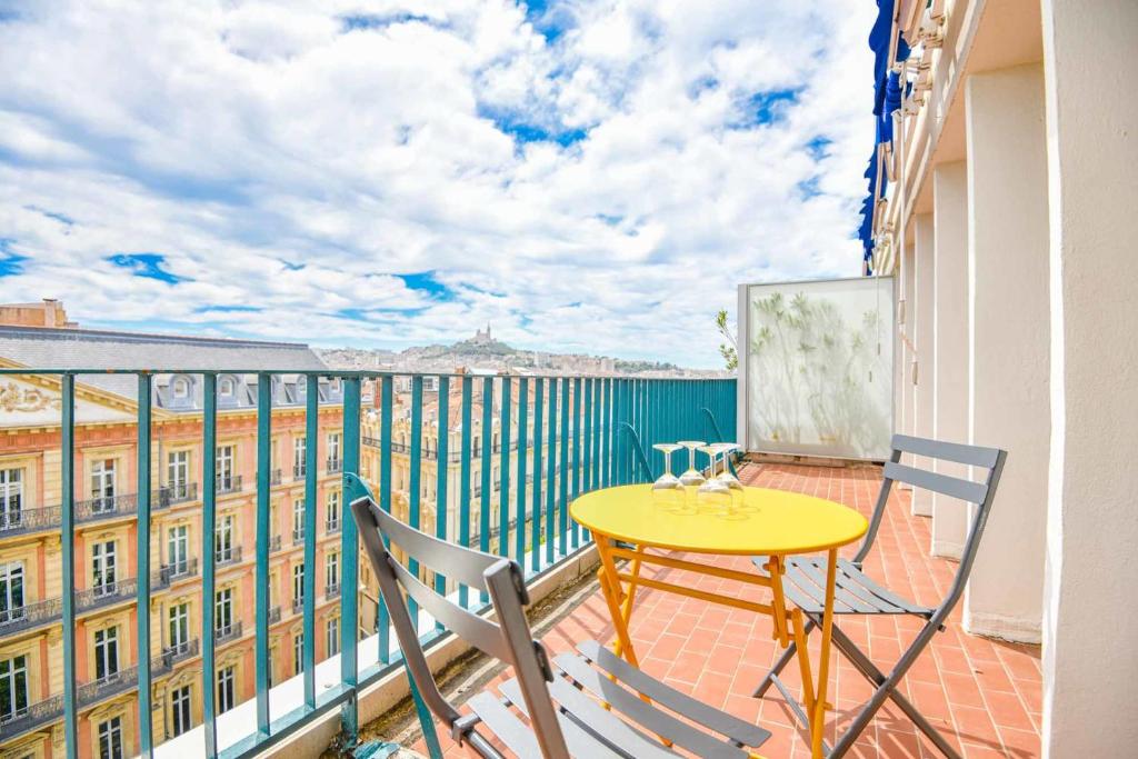 einen Balkon mit einem gelben Tisch und 2 Stühlen in der Unterkunft La Canebière - Appart 2 chambres avec terrasse in Marseille