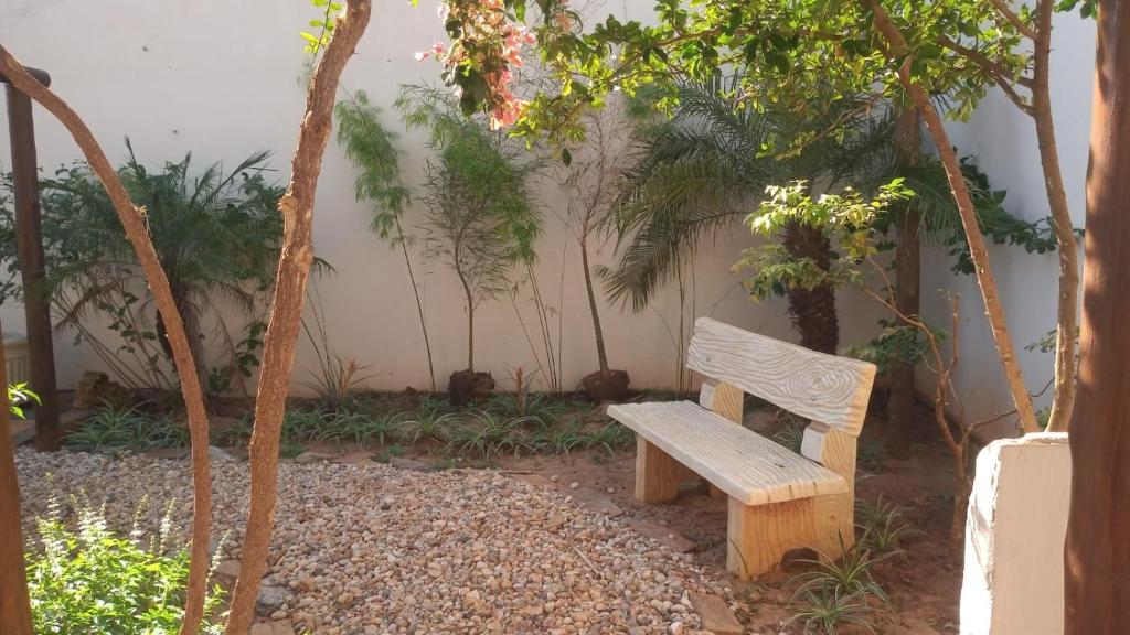 una panchina di legno seduta in un giardino alberato di Casa Caluca a Olímpia