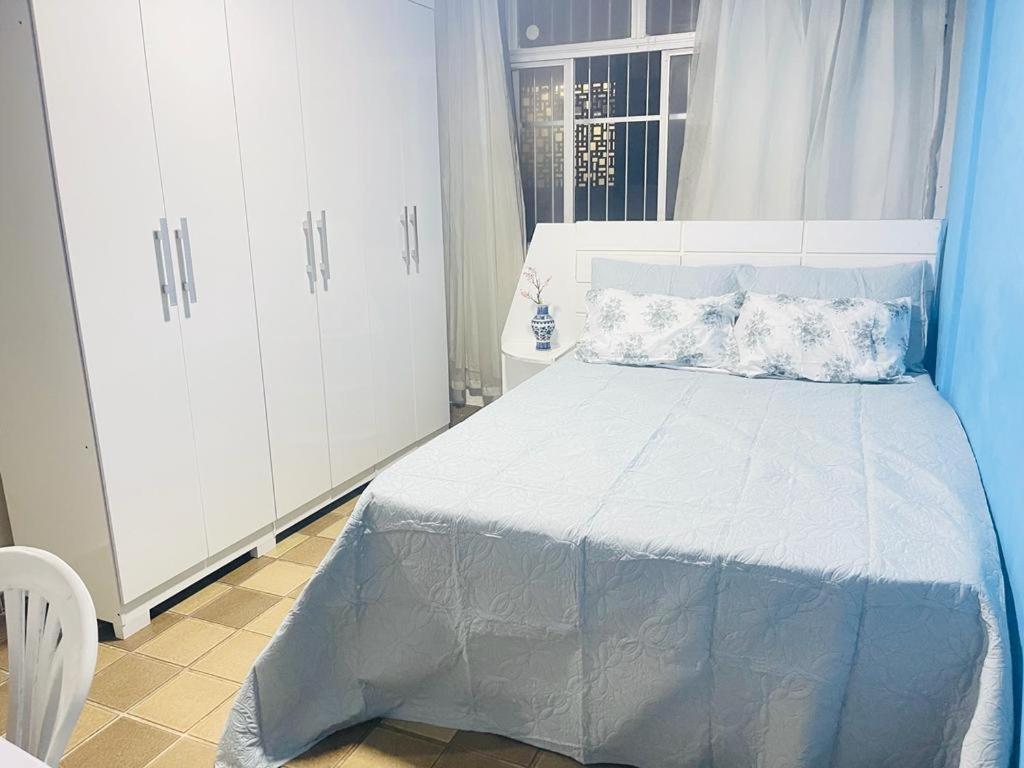 um quarto com uma cama, armários brancos e uma janela. em Apartamento em Boa Viagem no Recife