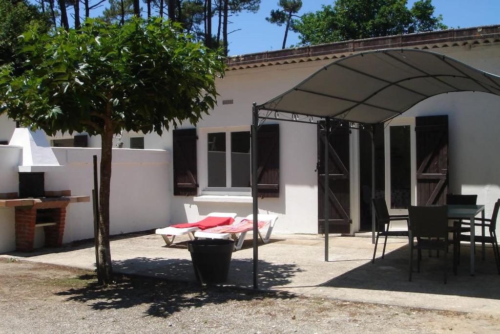 a patio with a tent and a table and a tree at LES BRUYERES in Léon