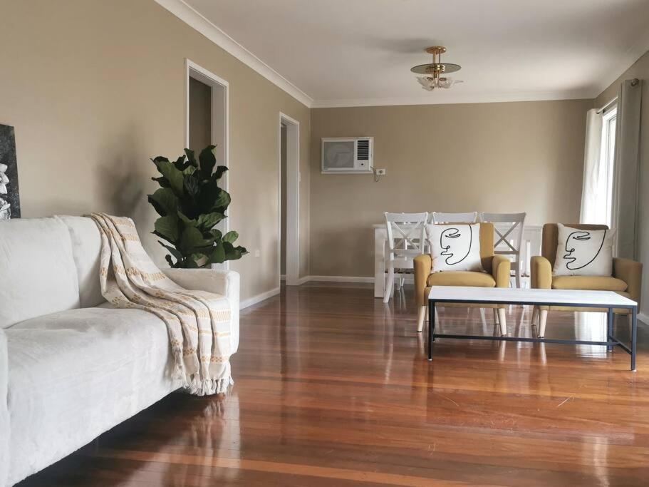 een woonkamer met een witte bank en stoelen bij Home Plus TAREE CBD in Taree