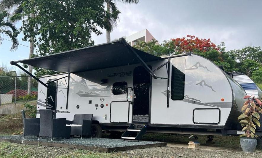 a white rv with a black roof parked in a yard at Buye Campers in Cabo Rojo