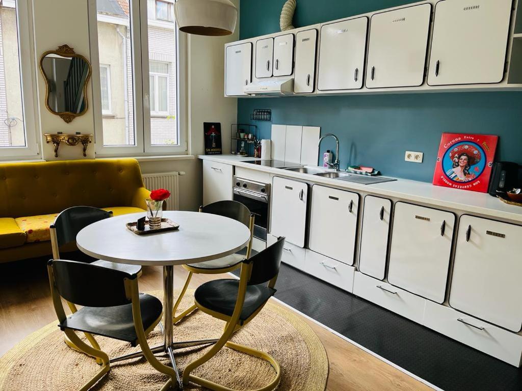 a kitchen with white cabinets and a table and chairs at foodiejive appartement 2 in Antwerp