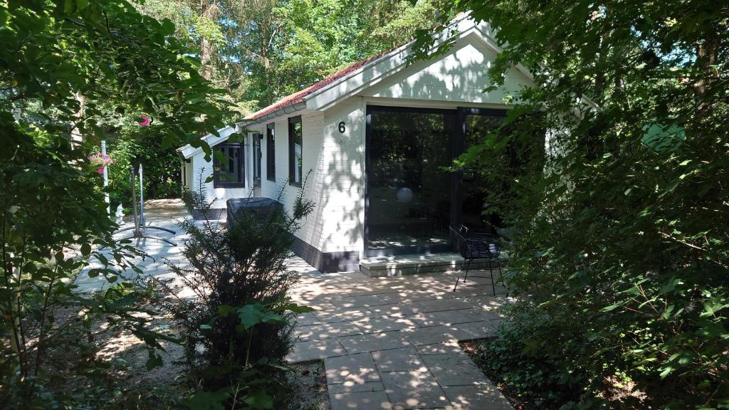 una casa bianca con una grande porta scorrevole in vetro di Relaxed Luxery forest view bungalow with Jacuzzi a Hattemerbroek