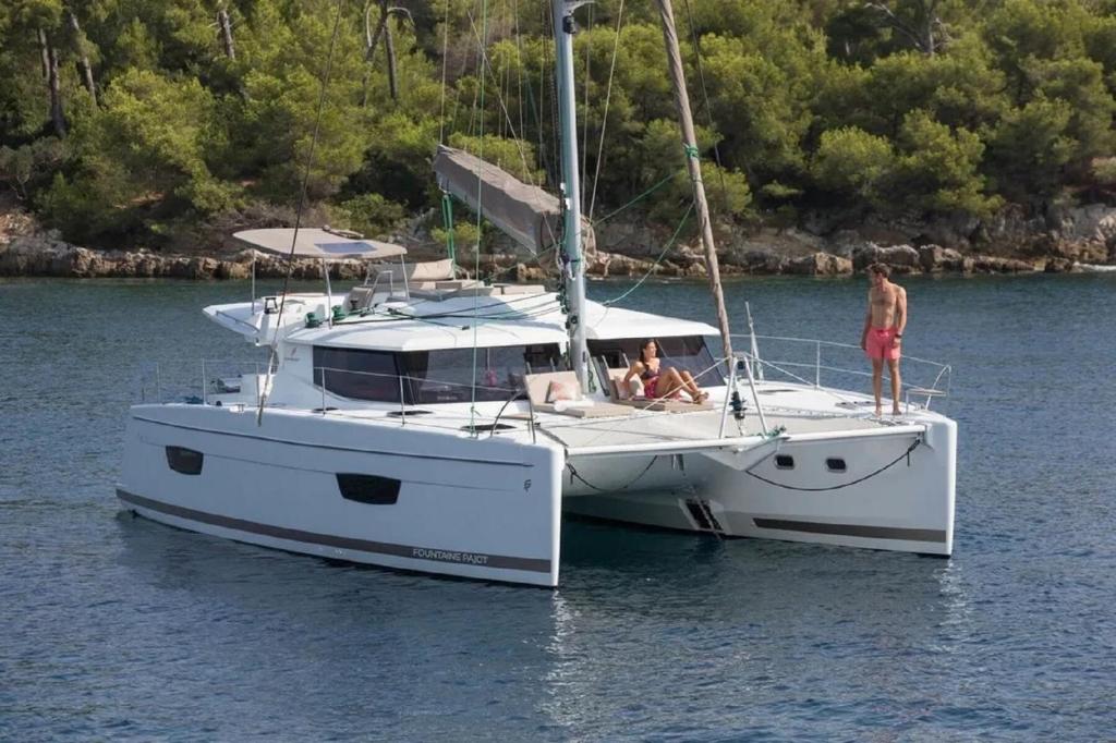 two people are sitting on a boat in the water at Placencia Sailing Catamaran Day Charter « Gingembre » in Placencia Village