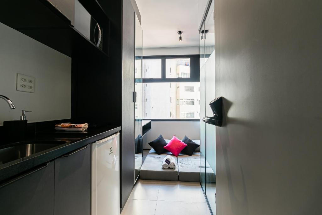 una cucina con lavandino e una finestra con divano di Novo e Brilhante Studio em Higienópolis-Academia a San Paolo