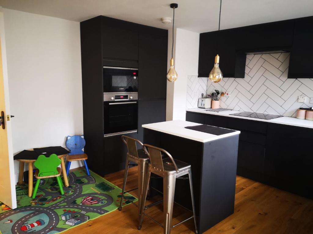 a kitchen with black cabinets and a counter and chairs at Home on the Shore in Edinburgh