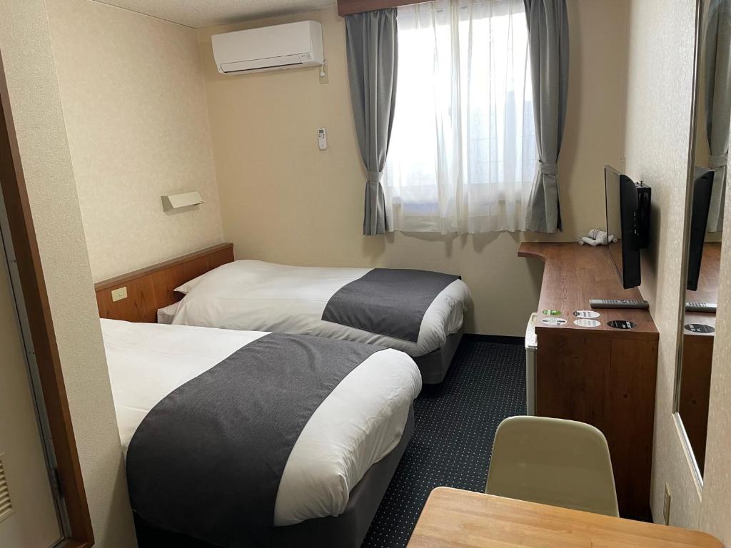 Habitación de hotel con 2 camas, mesa y TV en Atto Business Hotel Ichinoseki en Ichinoseki