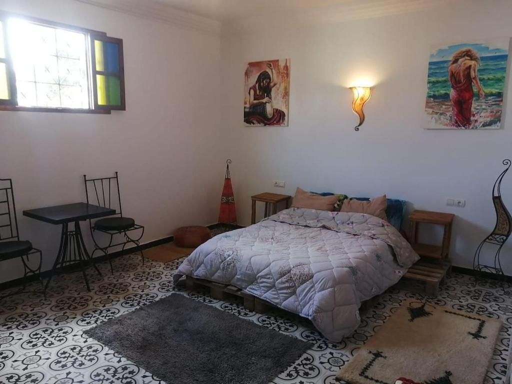 エッサウィラにあるMaison d'hôteのベッドルーム1室(ベッド1台、テーブル、窓付)