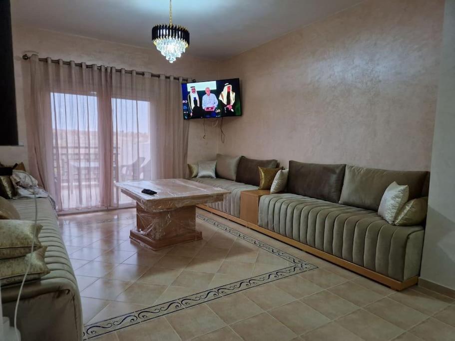 a living room with a couch and a tv at Appartement Saidia avec piscine in Saïdia