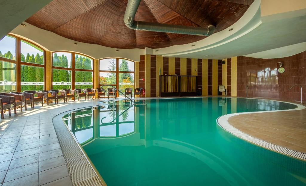 een zwembad in een hotel met stoelen en ramen bij Penzion Velky Meder in Dunajská Streda