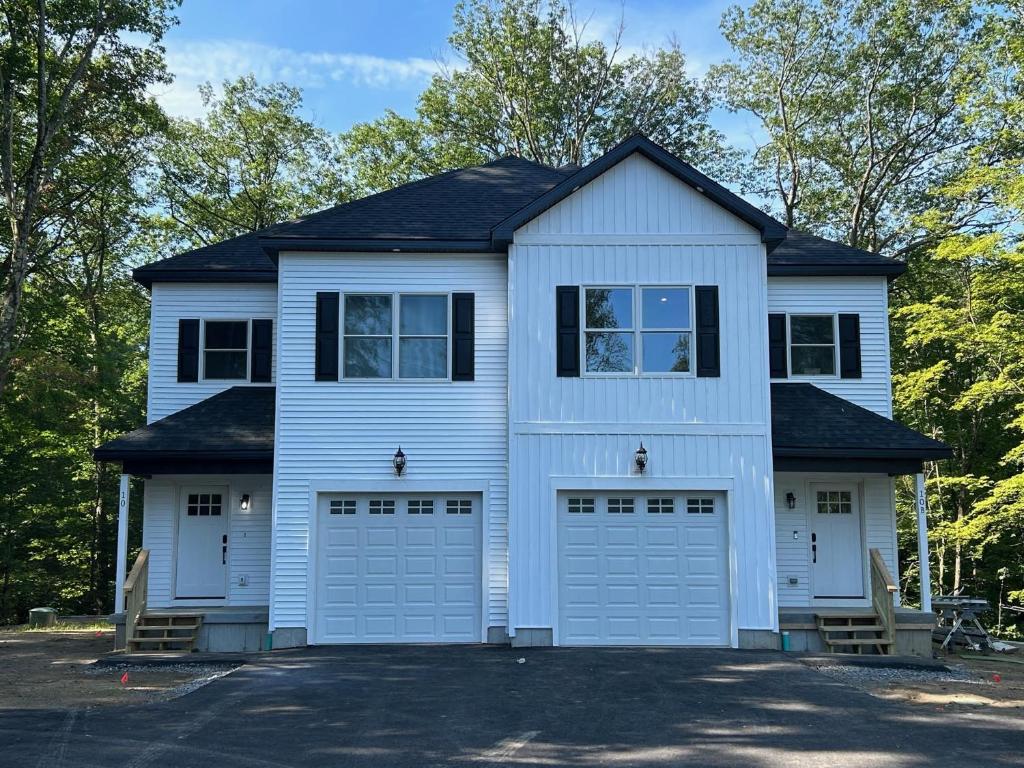 a white house with two garage doors at NEW 3 bedroom - Thoroughbred Farm & Lake Views! in Saratoga Springs