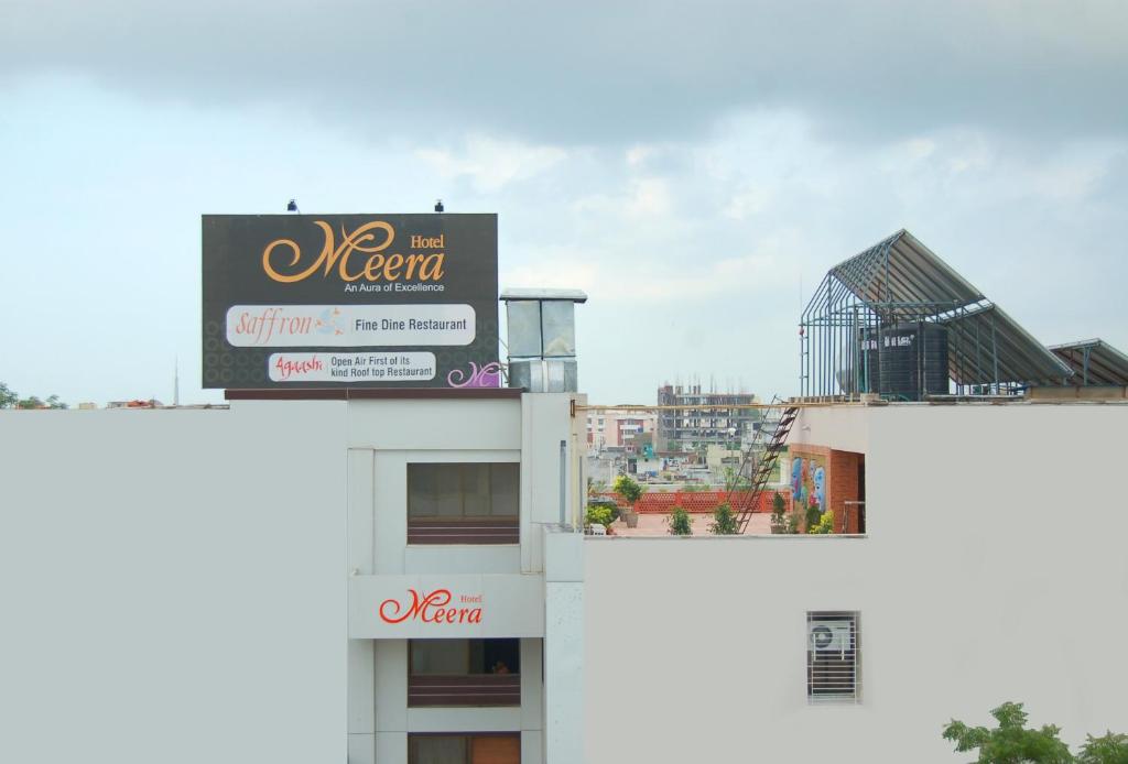 znak na szczycie białego budynku w obiekcie Hotel Meera w mieście Raipur