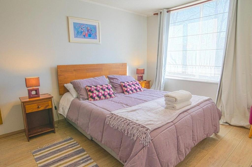 - une chambre avec un lit doté de draps violets et une fenêtre dans l'établissement TuArriendoCL-Vita A021 Centrico Depto Puerto Varas 1D1B hasta 3 PAX, à Puerto Varas