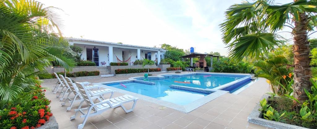 una piscina con sillas blancas y una casa en Extraordinaria CASA FINCA Piscina AA en Sabanalarga