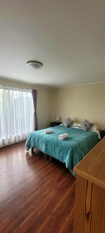 a bedroom with a large bed with a green blanket at Hospedajes Roma in Valdivia