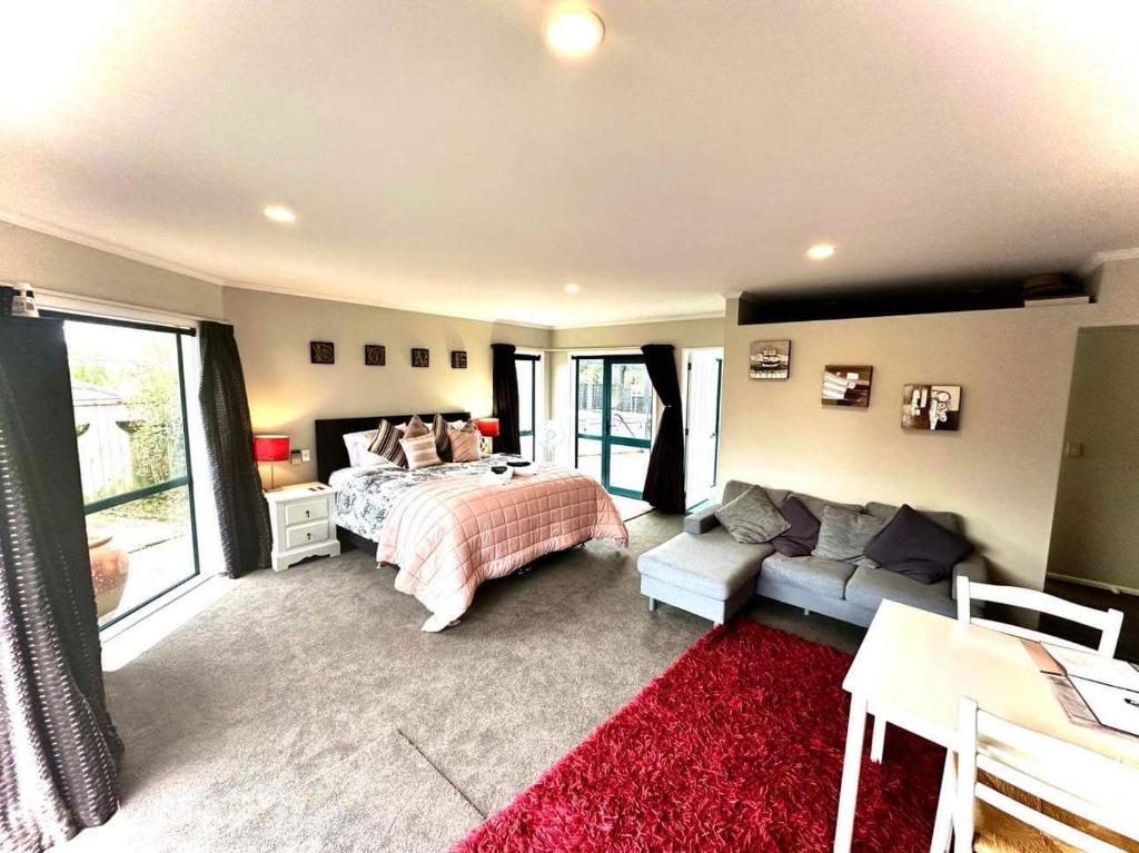 a bedroom with a bed and a couch at Observation Guest Suite in Paraparaumu