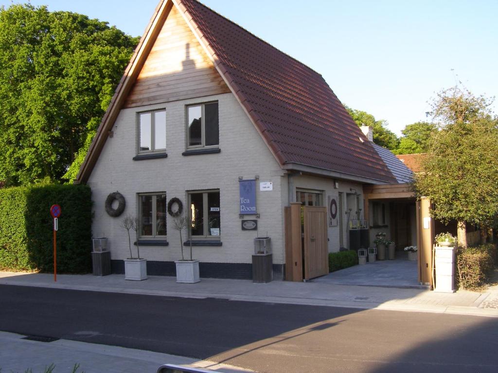 un petit bâtiment blanc avec un toit brun dans l'établissement Huyze-peppins, à Maldegem