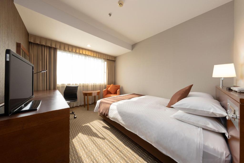 a hotel room with a bed and a flat screen tv at Meitetsu Grand Hotel in Nagoya