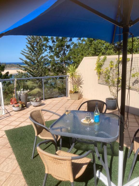 a table with chairs and an umbrella on a patio at Oceanview4 in Nambucca Heads