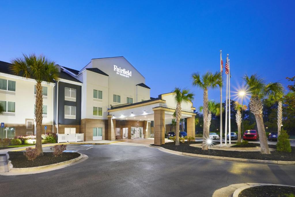 a hotel with palm trees in front of a building at Fairfield Inn & Suites By Marriott Hinesville Fort Stewart in Hinesville