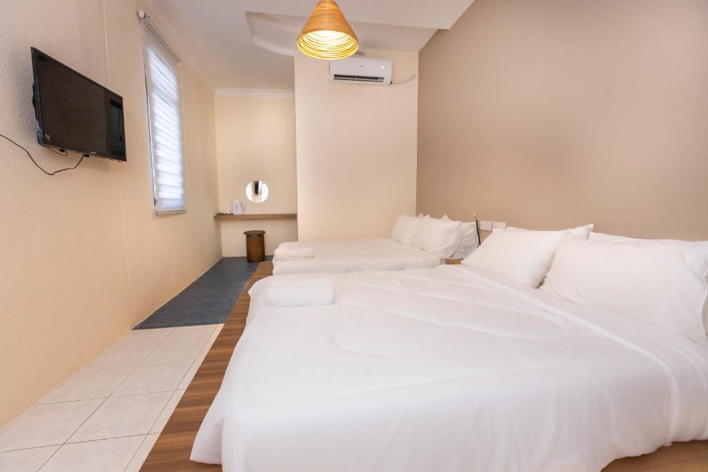 una camera con un grande letto bianco e una TV a schermo piatto di The Bahari Lodge @ Georgetown a George Town