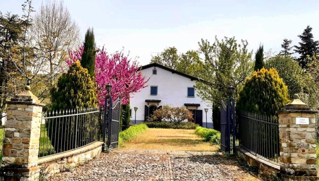 a white house with a black fence and trees at Casa Stella Country House in Savigno