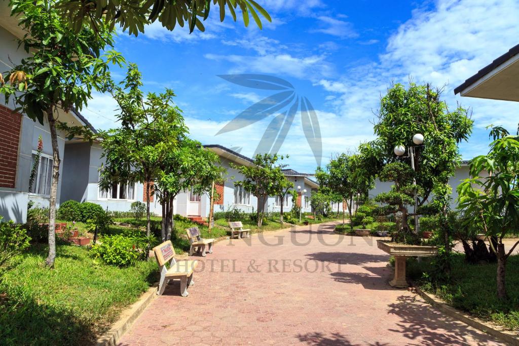 Tre Nguồn Thiên Cầm Hotel&Resort في Hưng Long: ممشى فيه كراسي واشجار في حديقة