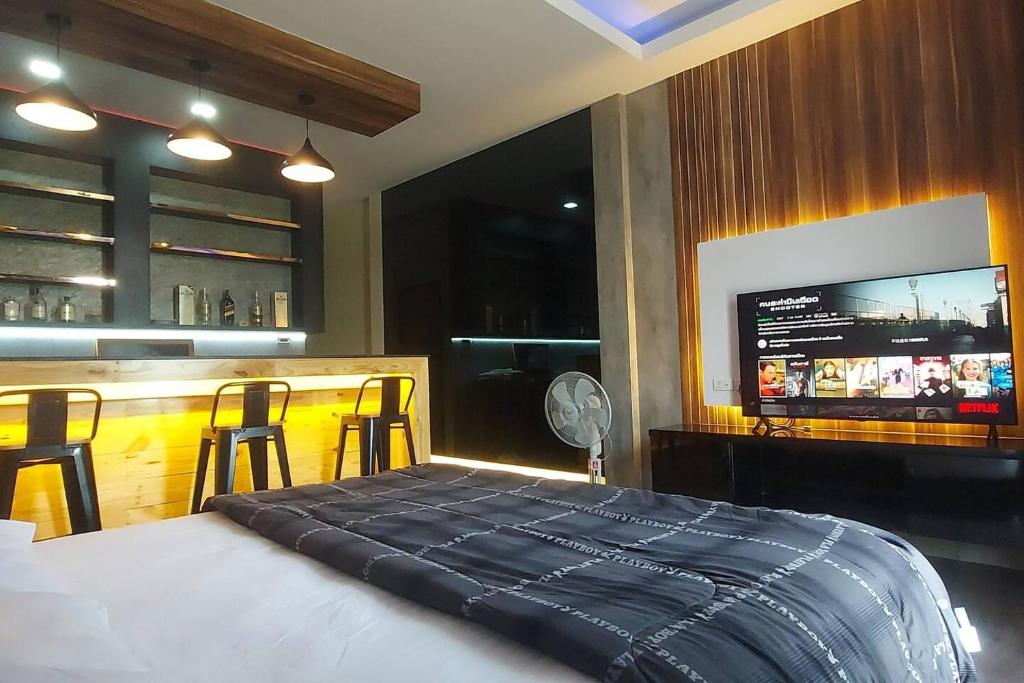 a bedroom with a bed and a bar with a tv at Lanmuanghouse in Chiang Rai