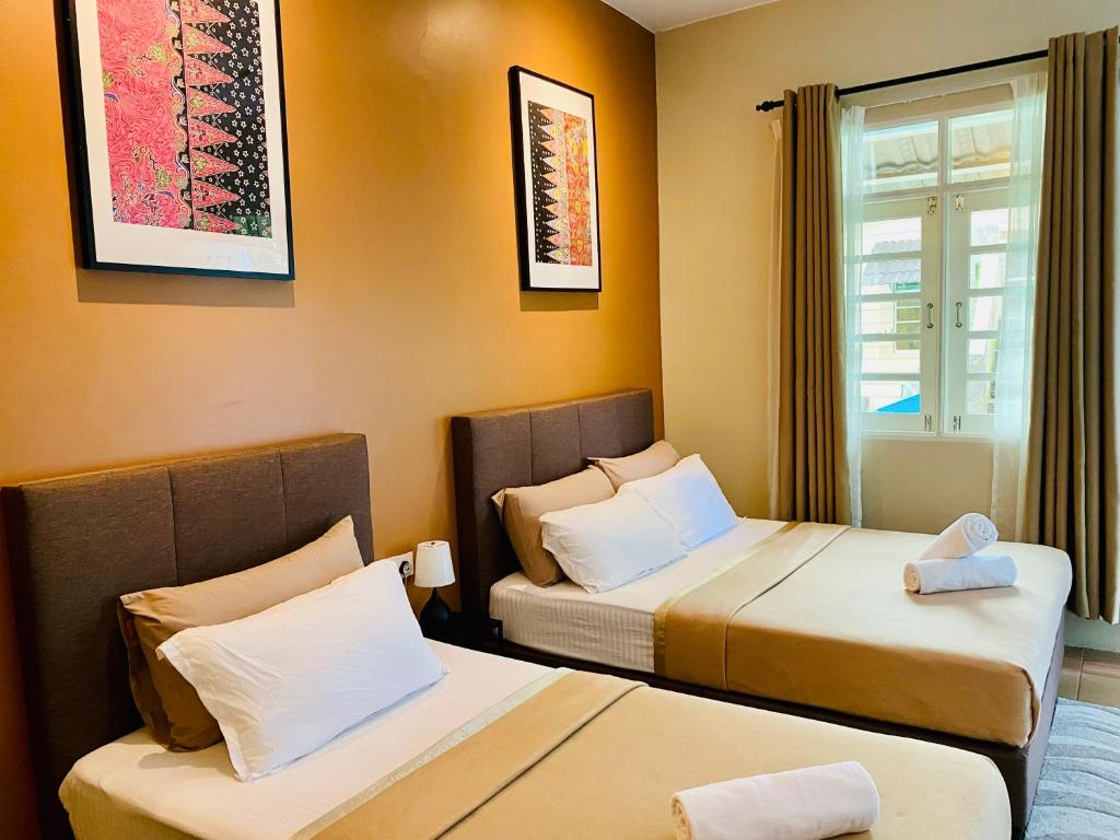 a hotel room with two beds and a window at Gading Chalet in Kuala Terengganu